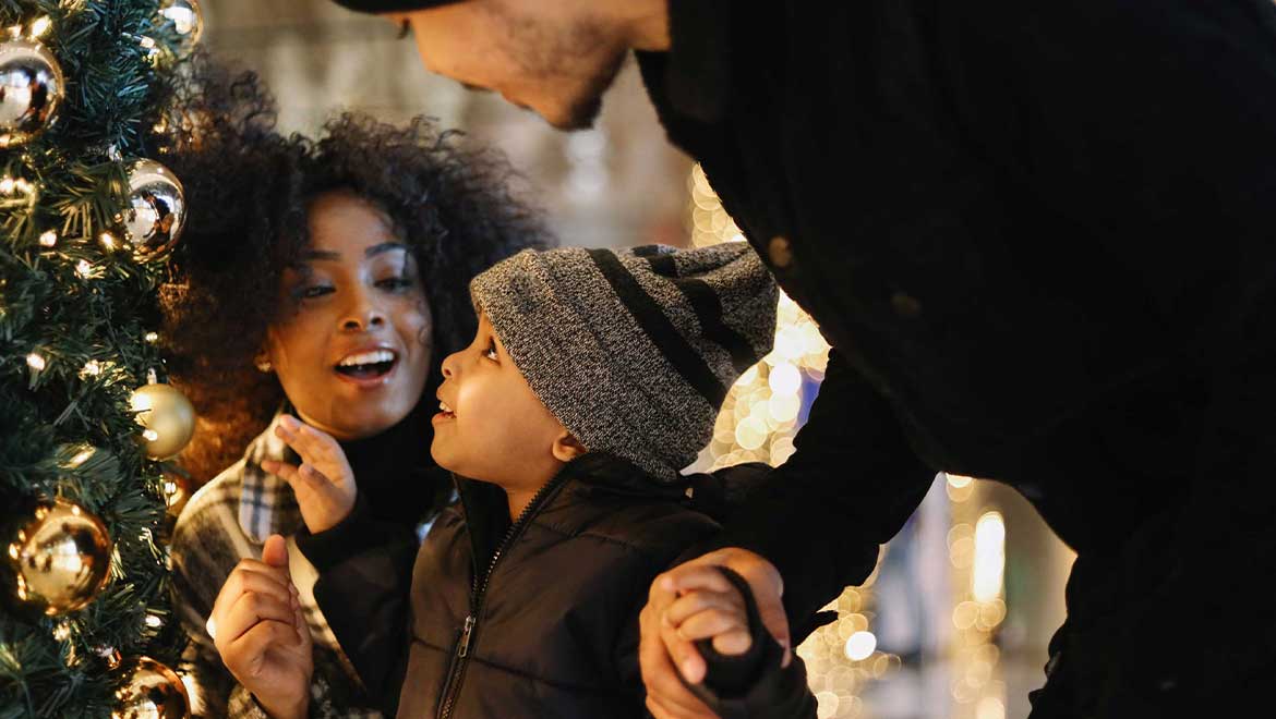 Family of three admiring a Christmas tree