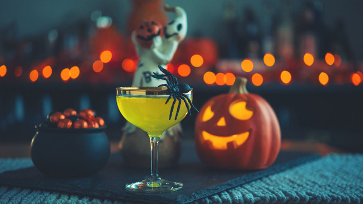 Drink with a spider on it and a carved pumpkin. 