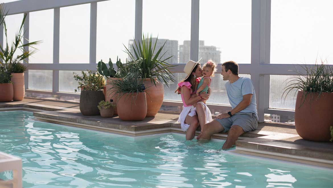 Family of three sitting by the pool 