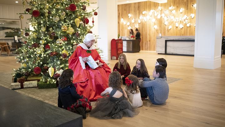 Character reading stories by the Christmas tree.