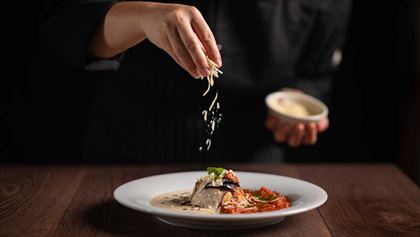 Chef adding cheese to a plate of food