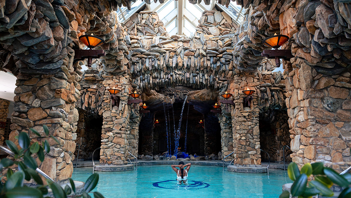 A woman in a spa pool within a stone grotto - omni grove park inn